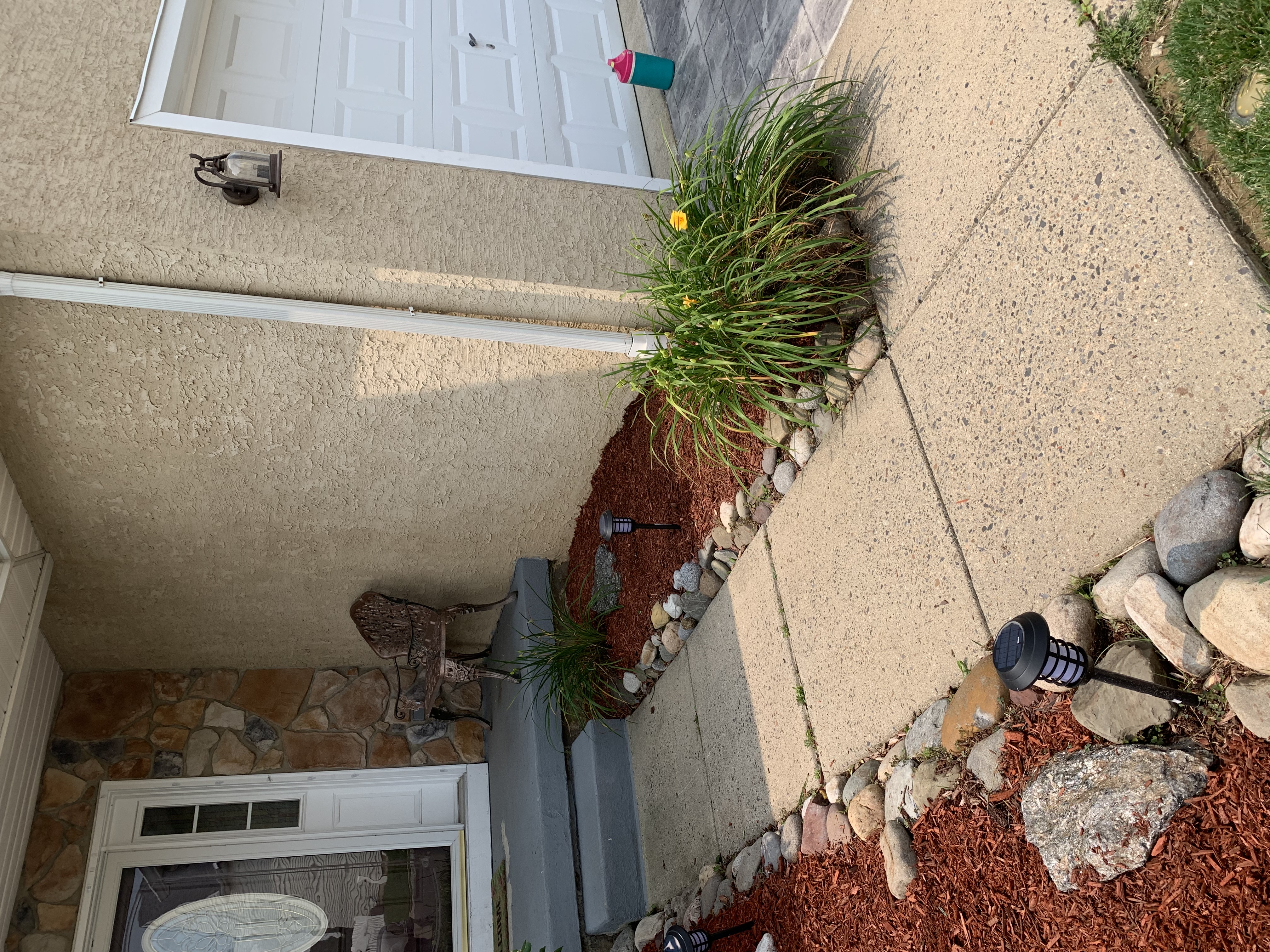 Side yard with river rock, daylilies, and driveway border