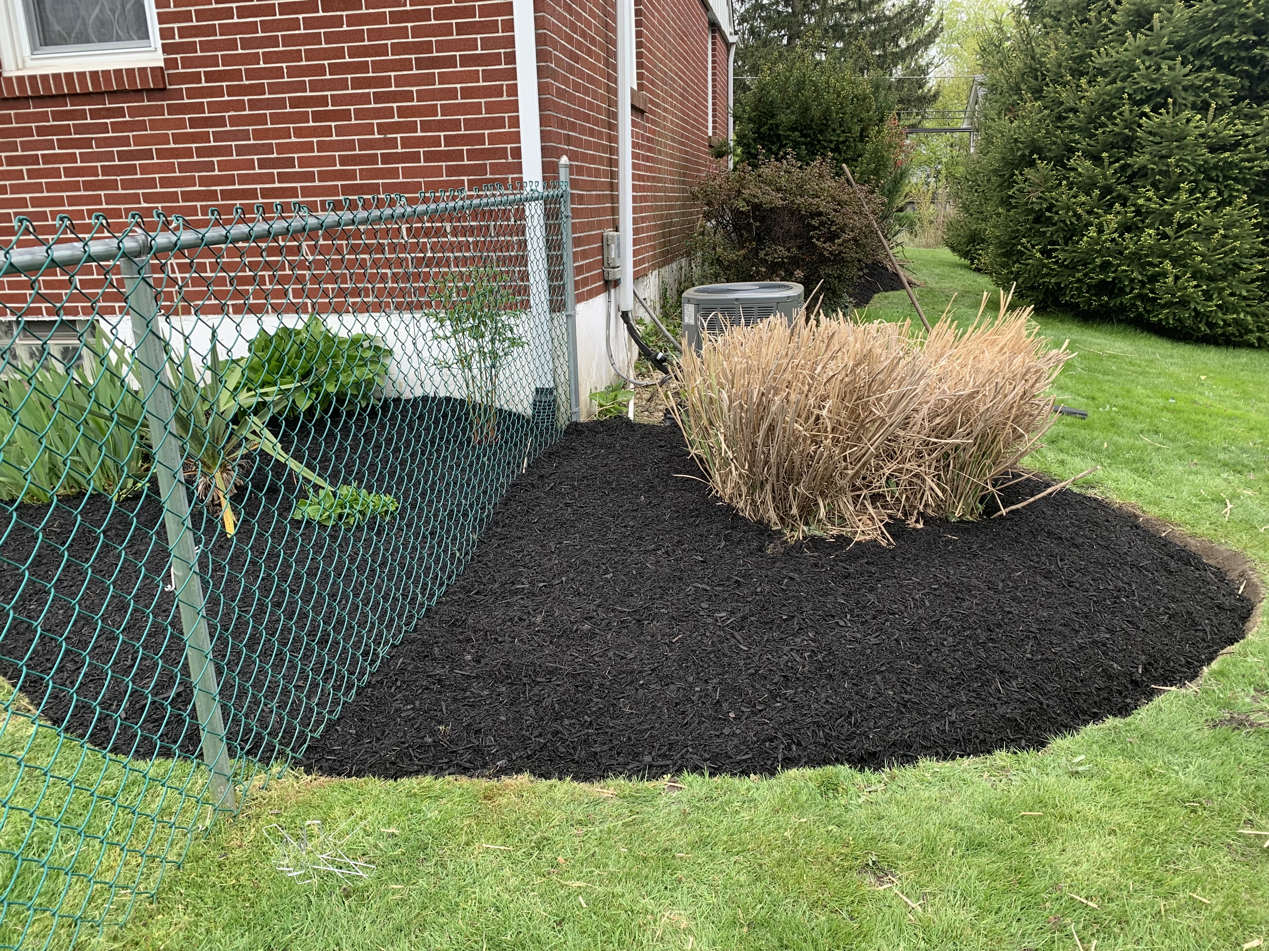 Mature plantings with fresh mulch along brick wall